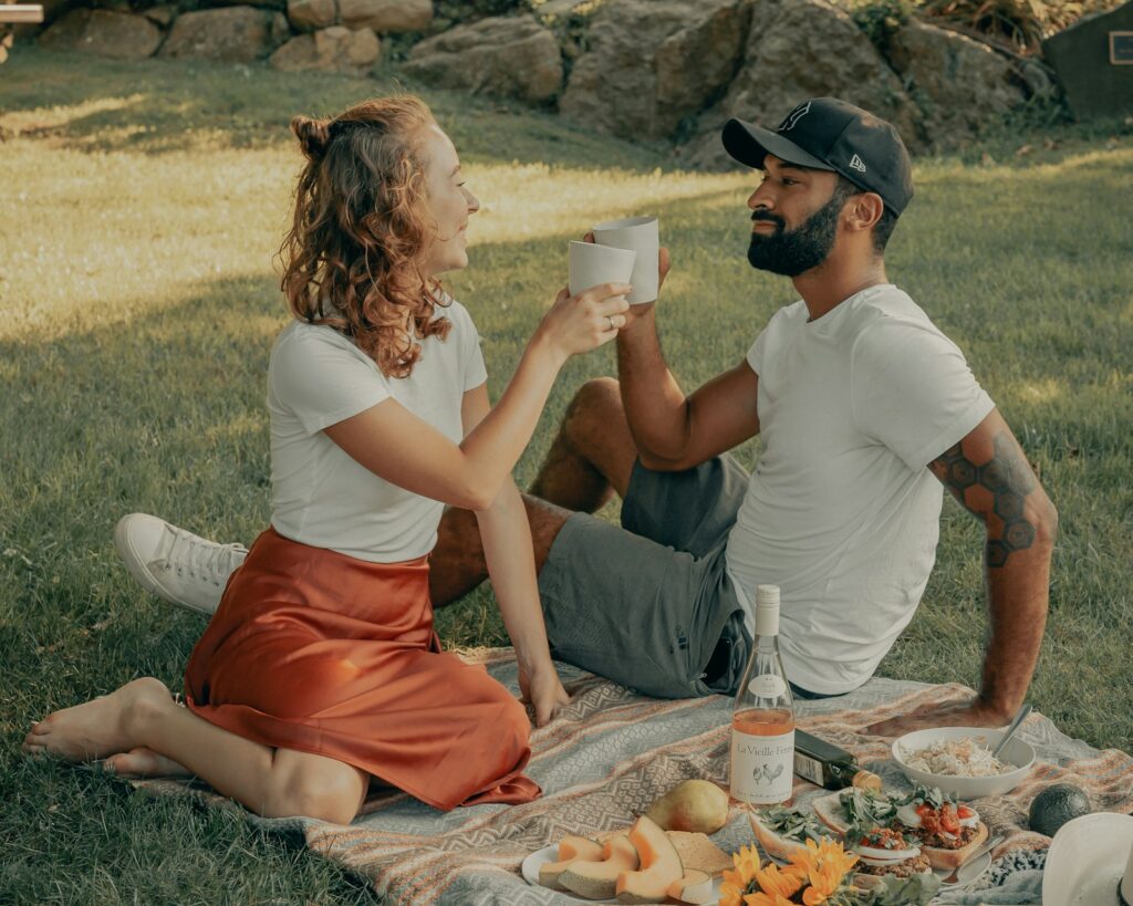 Man and woman sitting on ground with food on ground during daytime